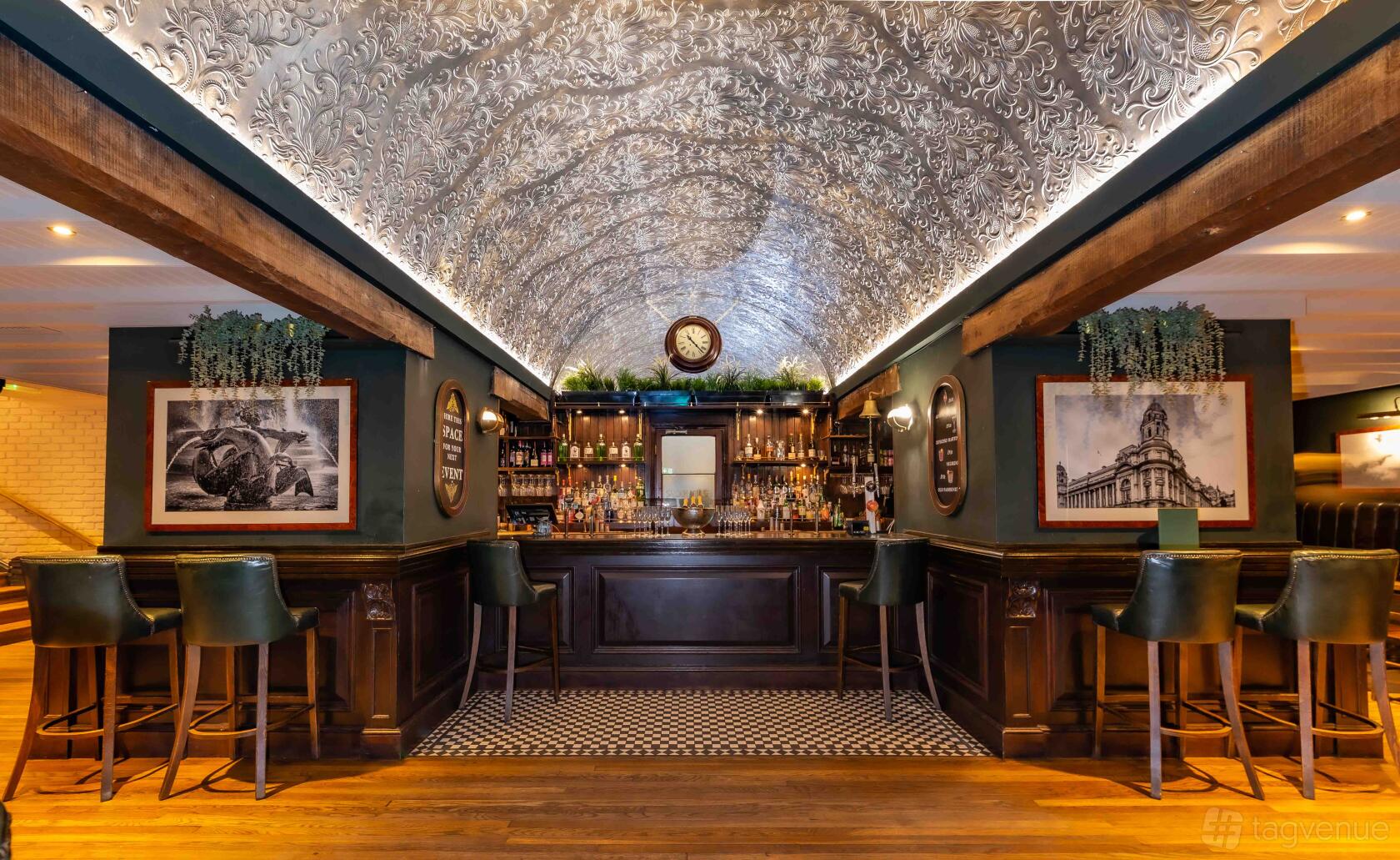 An event space in a pub with an ornate vaulted ceiling, wood bar, and leather barstools at Walkers of Whitehall.