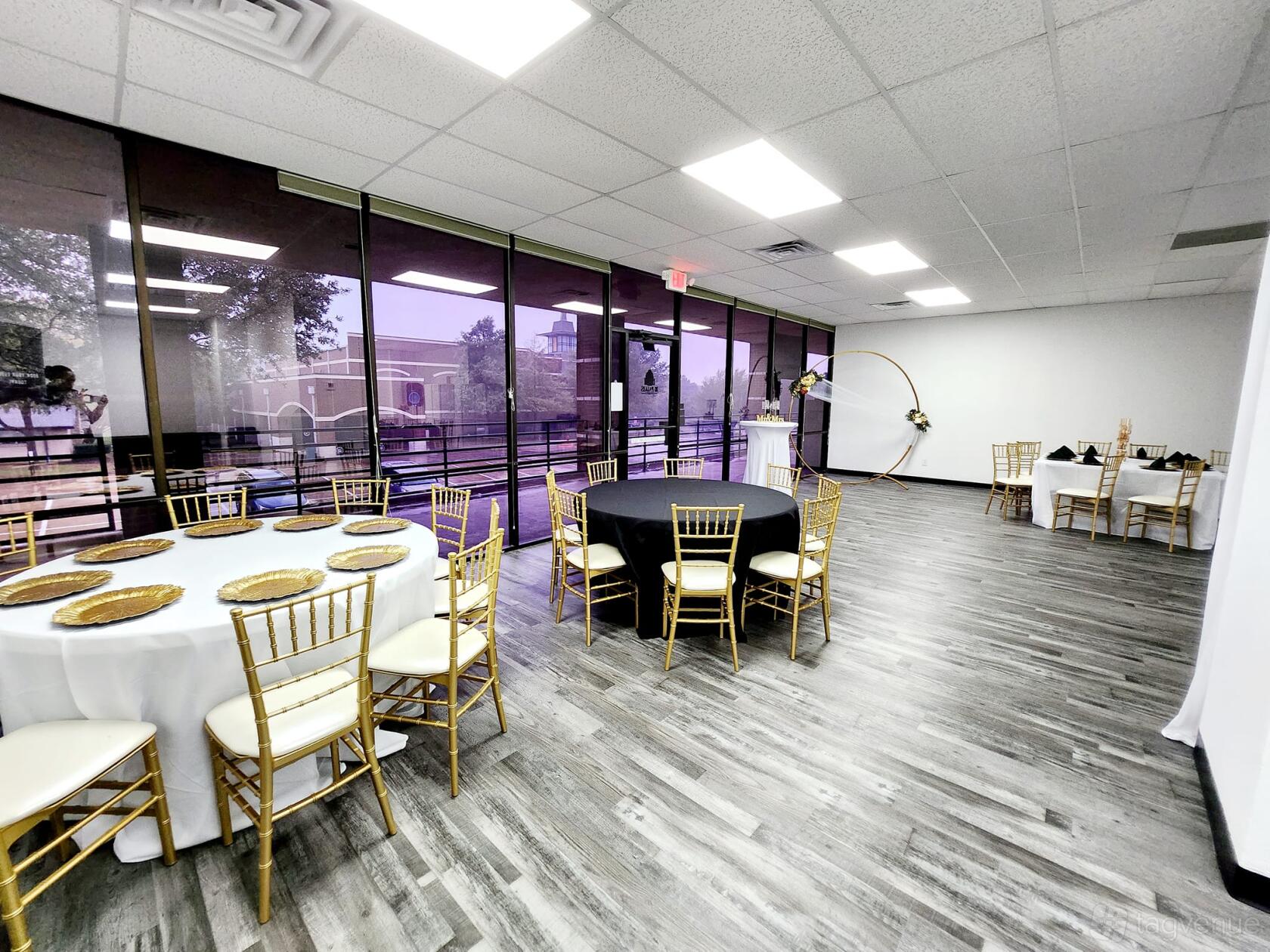 An event venue with floor-to-ceiling windows, gold Chiavari chairs, and round tables at Le Palais Events.