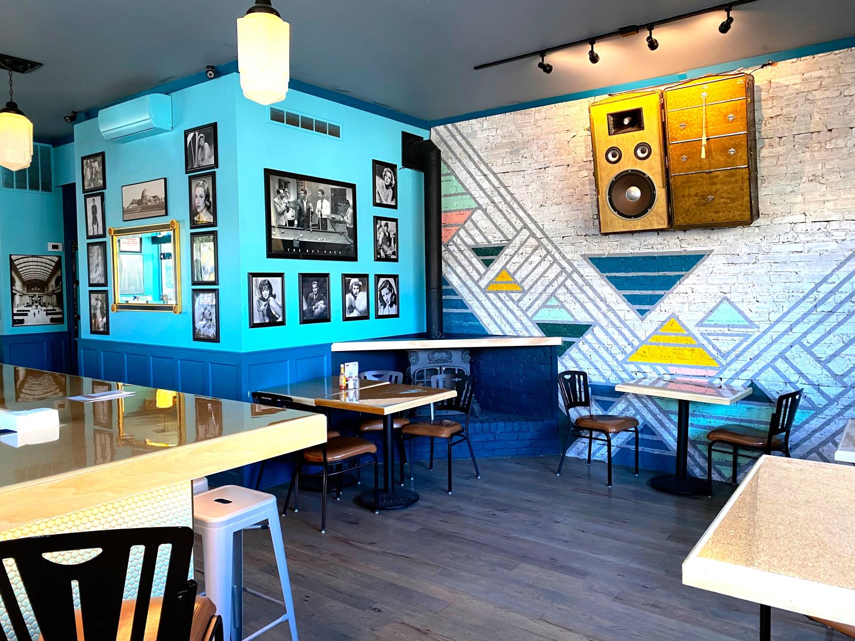 A function room with photo gallery walls, geometric mural, and wood tables at Port and Park Bistro.