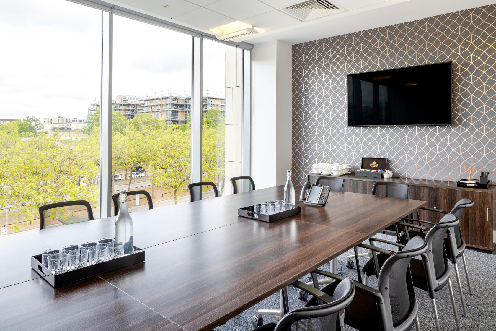 A meeting room with a large wooden conference table, patterned accent wall, and floor-to-ceiling windows at Landmark: Pinnacle, Milton Keynes.