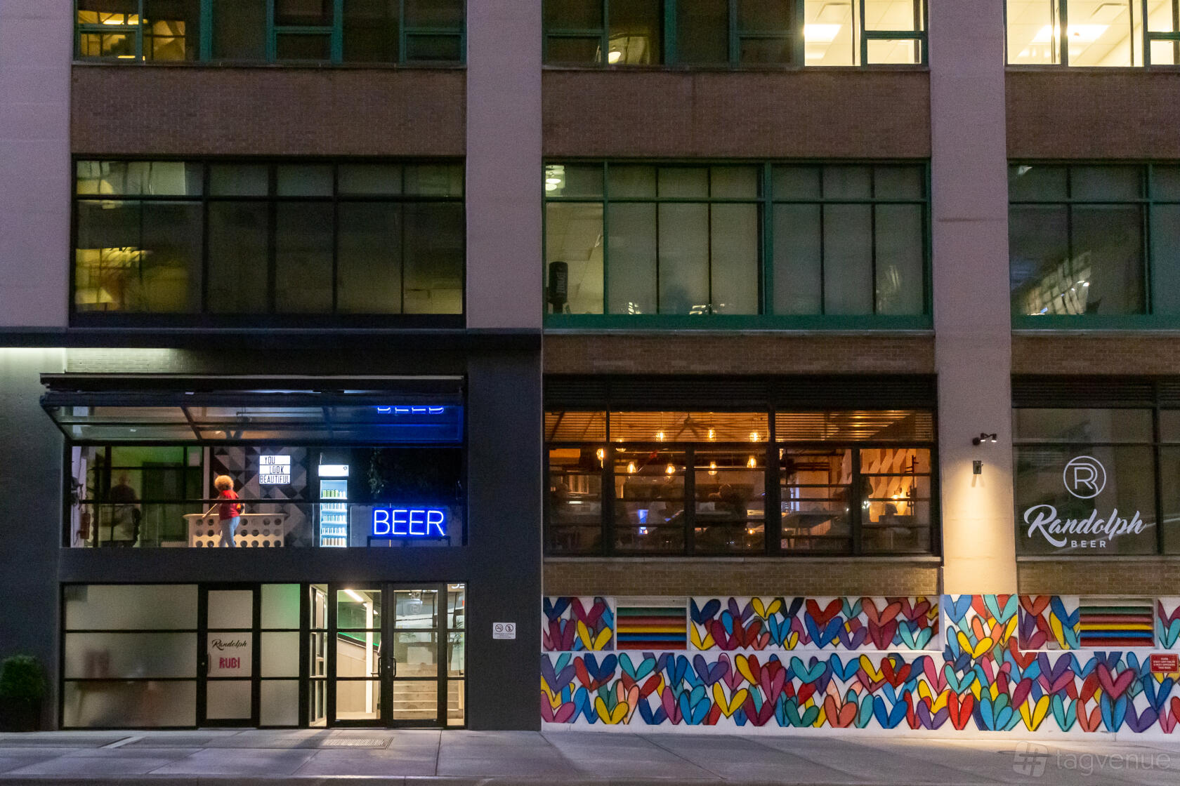 A pub exterior with neon signage and a colorful heart mural at Randolph Beer DUMBO.