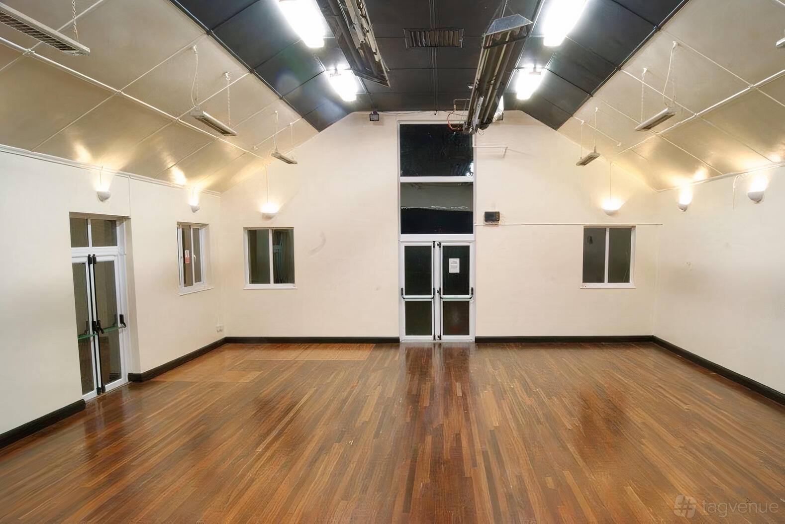 A hall with polished wooden floors, cream walls, and uplighting at The Woodside Park Club.