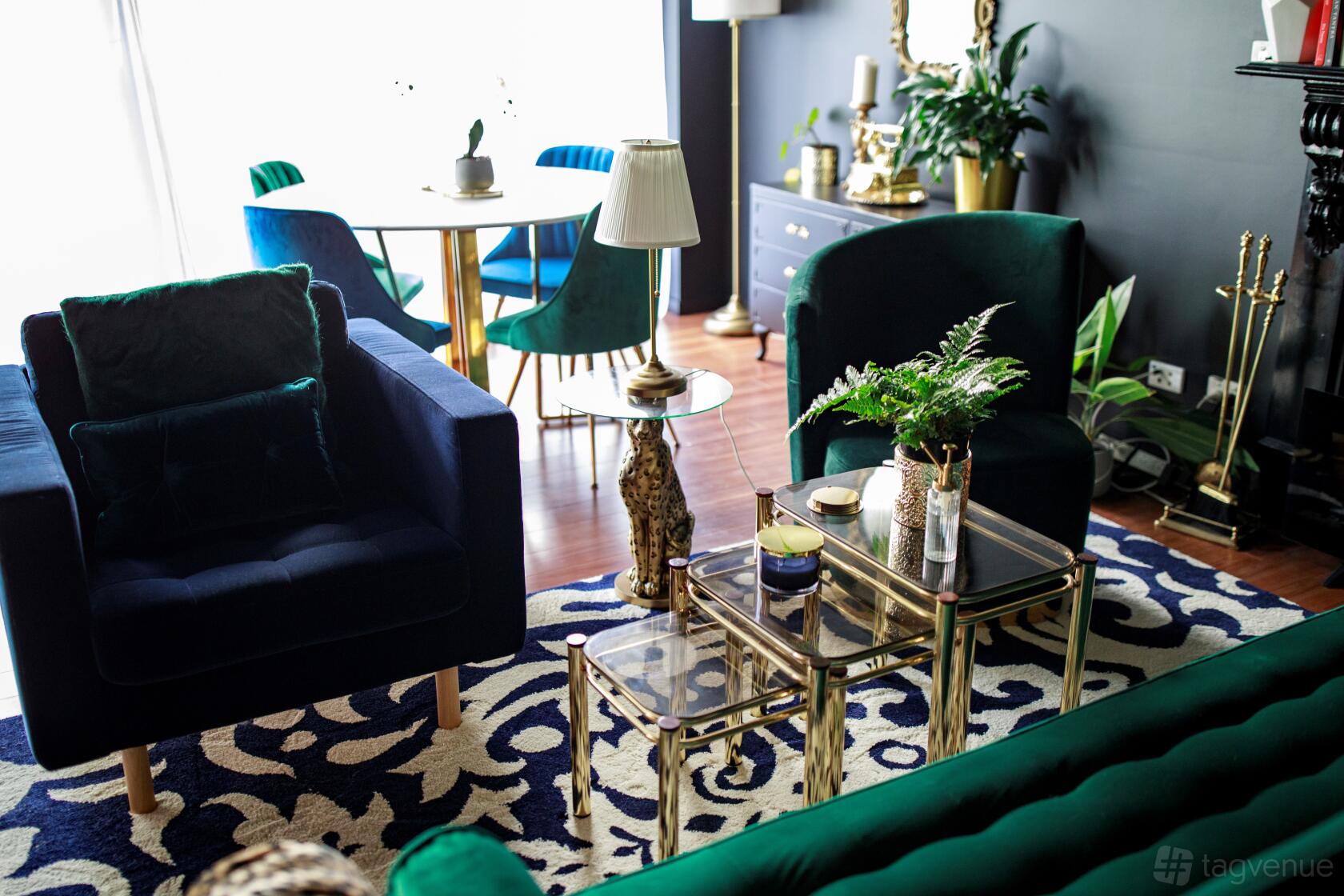 A photo studio with velvet armchairs, glass coffee tables, patterned rug, and ample natural light at Goddess Studio Noir.