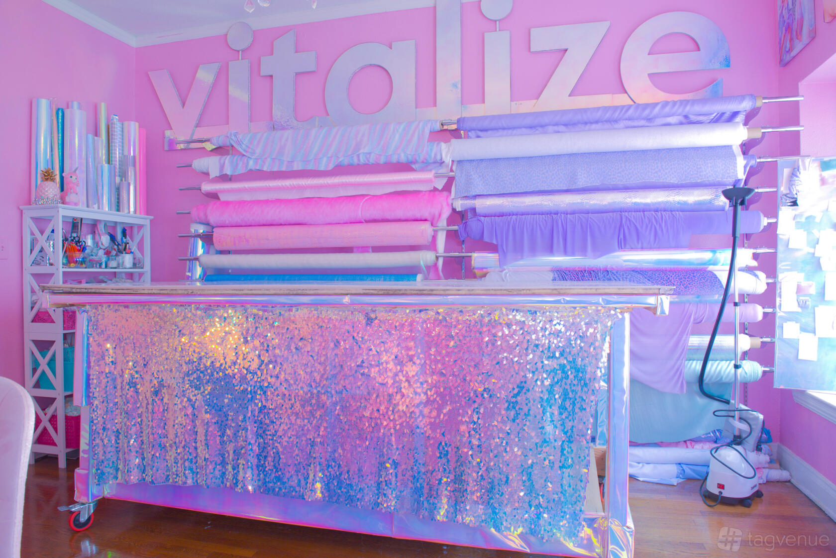 An event venue room with pink walls, shimmering sequin-covered table, and pastel fabric rolls at Sparkl Palace.