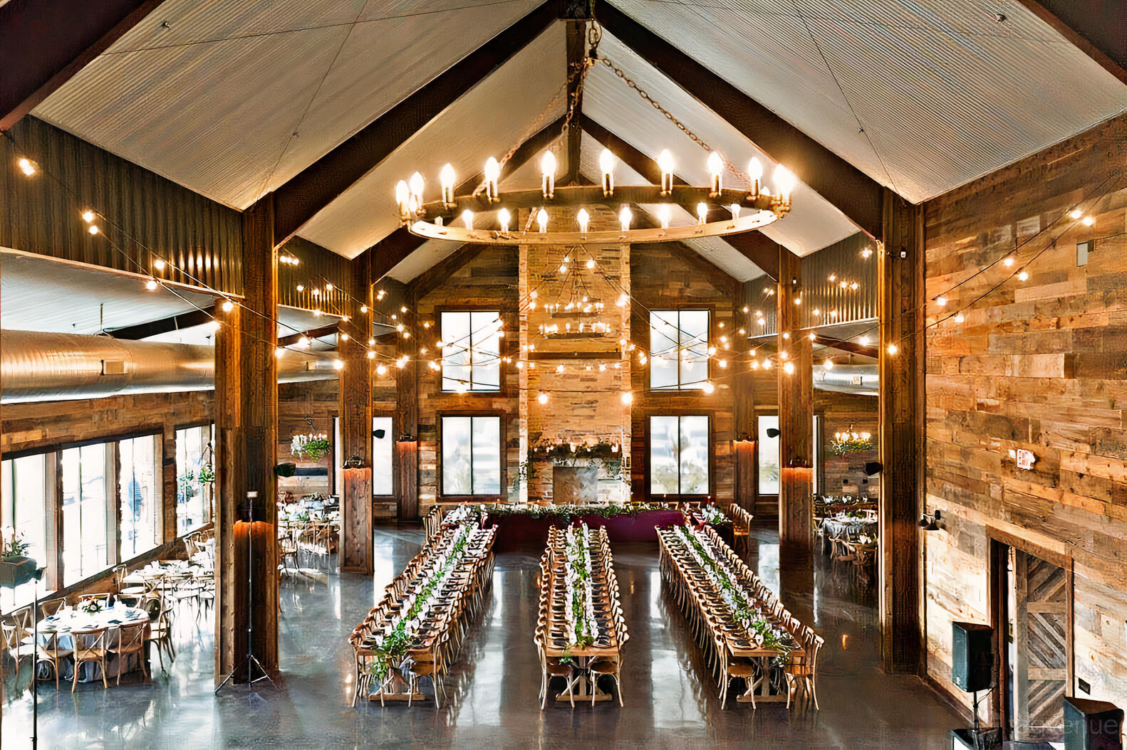 An event venue with high vaulted ceilings, rustic wood walls, chandeliers, and long banquet tables at Stone Crest Venue.