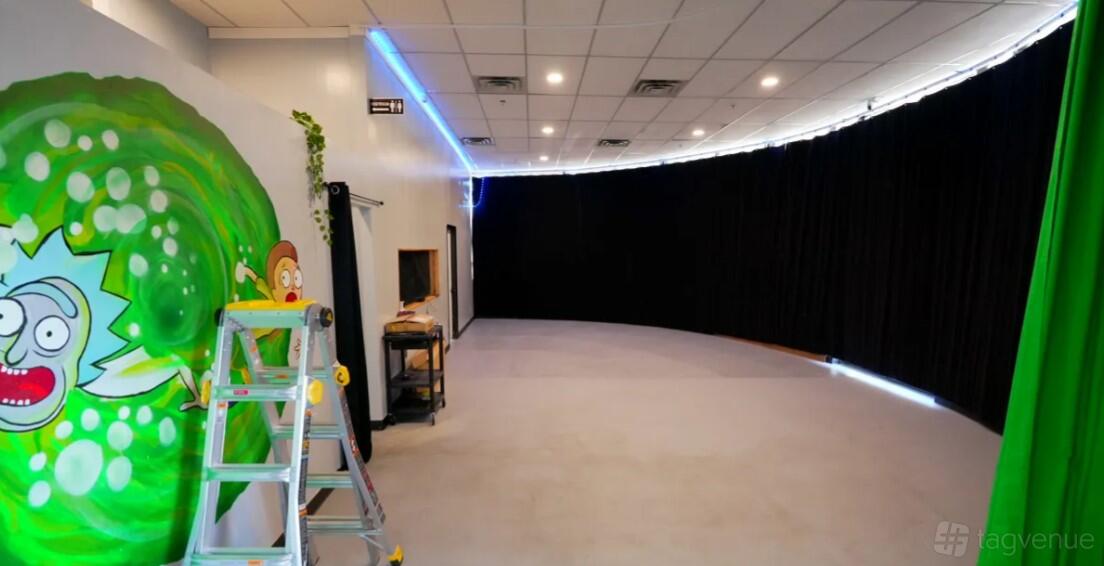 A photo studio with a mural wall, black-out curtains, and a step ladder at BoothMeUp Las Vegas.