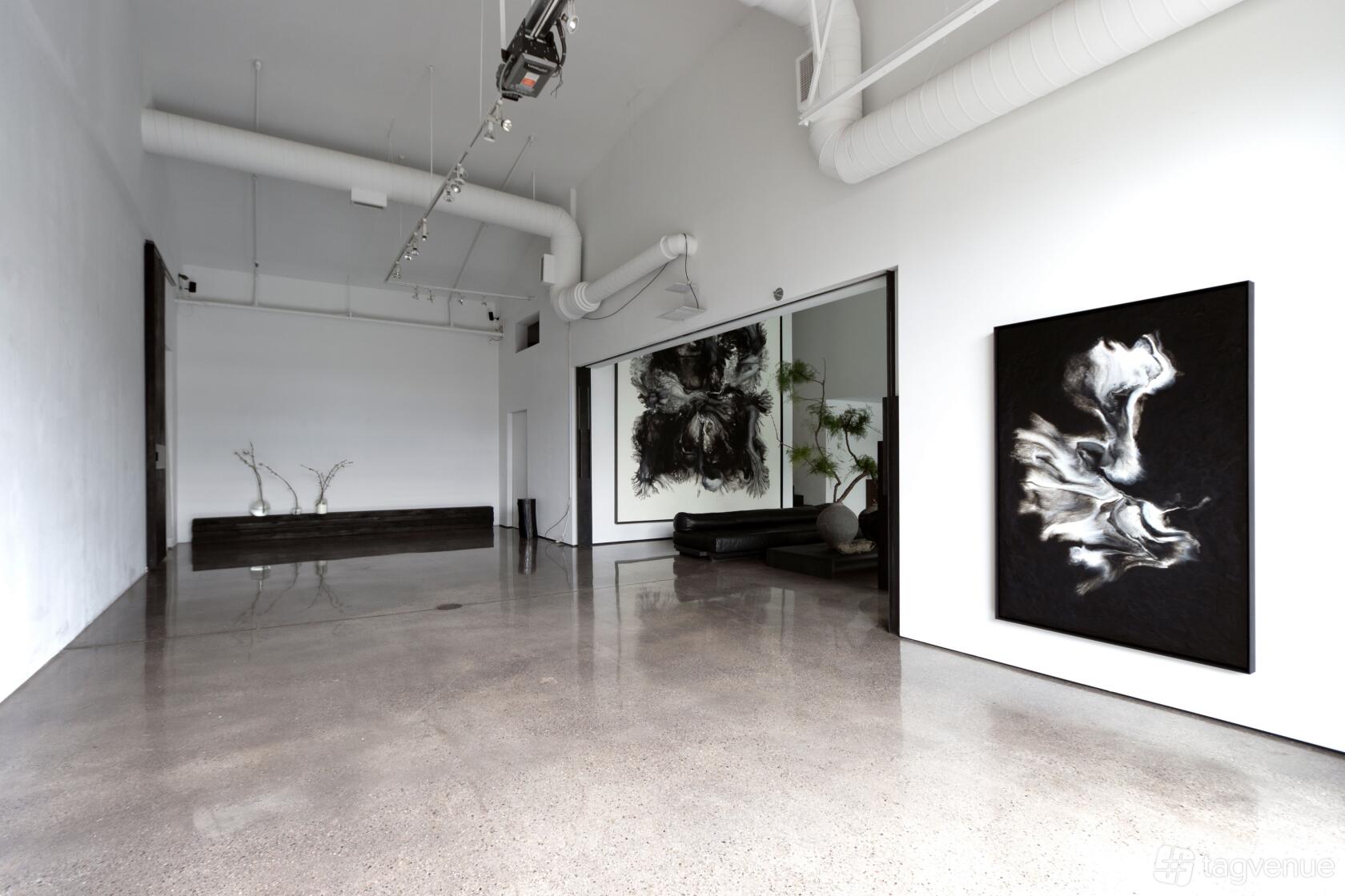 A photo studio with polished concrete floors, high ceilings, and abstract black-and-white artwork at White Studio.