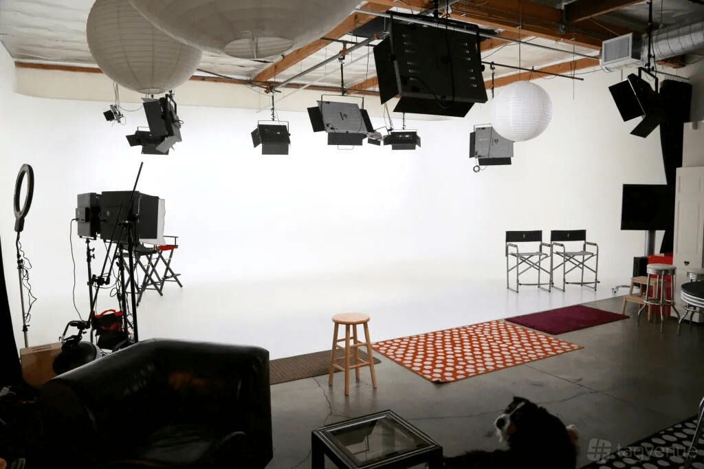A photo studio with a white cyclorama wall, overhead lighting, and director chairs at Underground Studios.