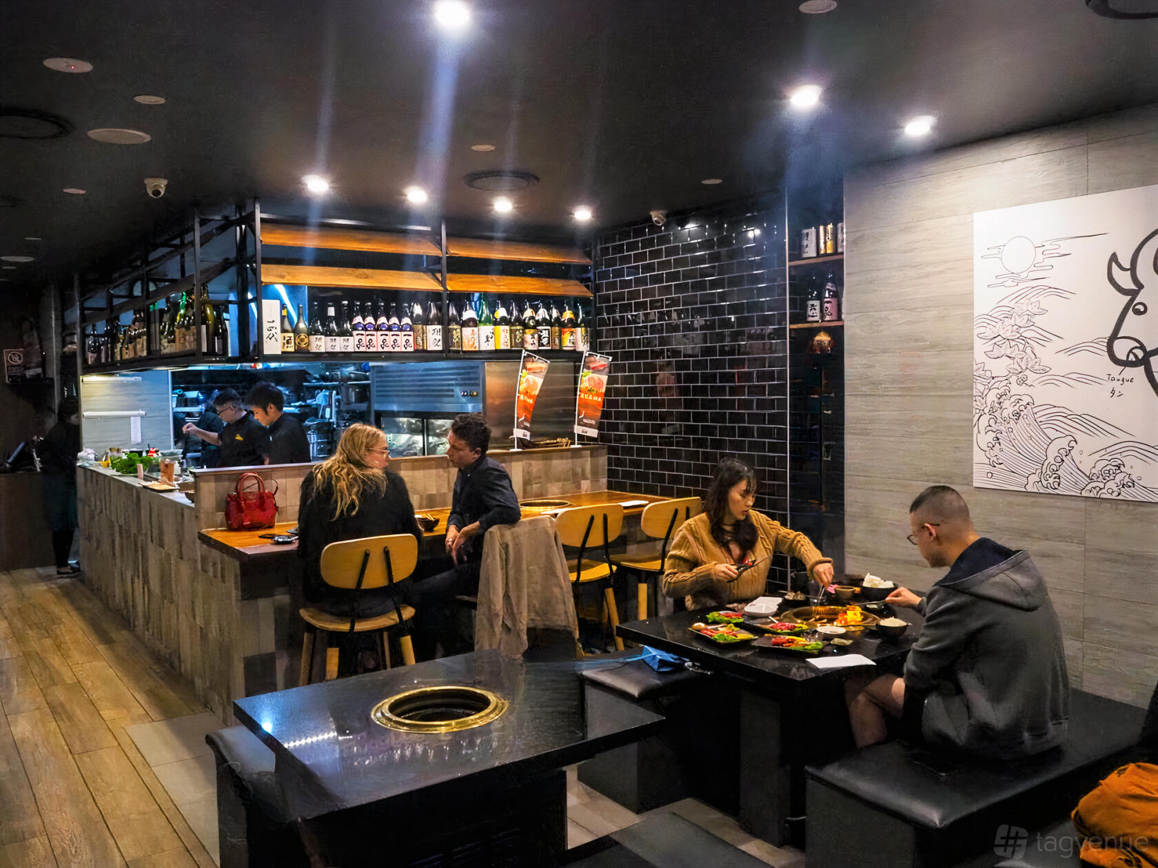 A restaurant with open kitchen, counter seating, black tiled wall, and tables for dining at Kagoshima Master Crows Nest.