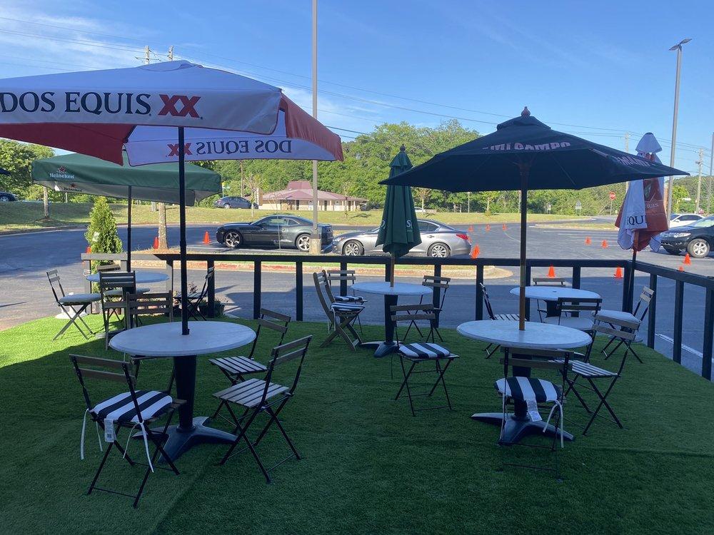 An outdoor restaurant patio with round tables, striped cushions, and large umbrellas at Access Restaurant and Lounge.