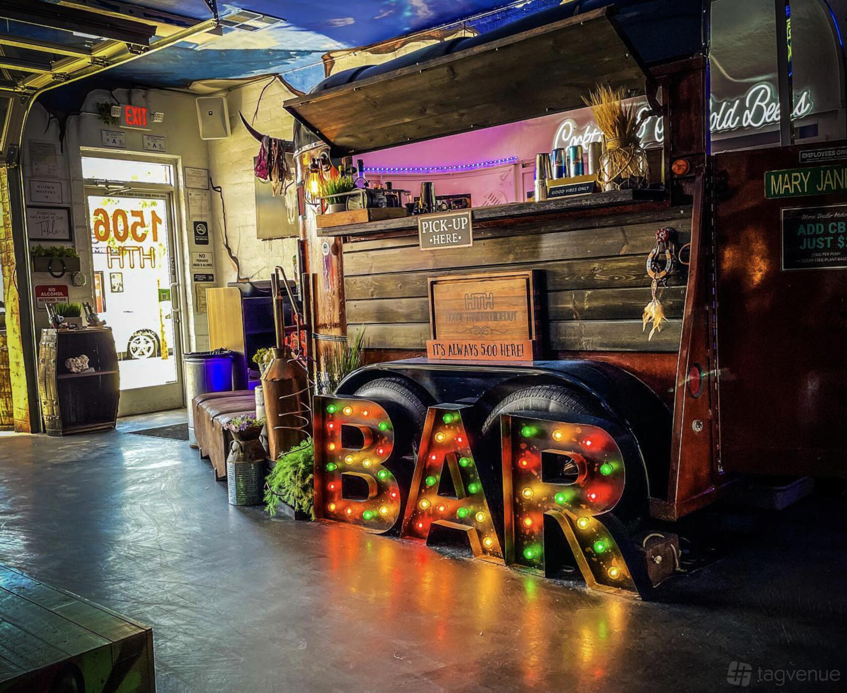 An event space with a vintage horse trailer bar, marquee BAR sign, and eclectic decor at Horse Trailer Hideout.