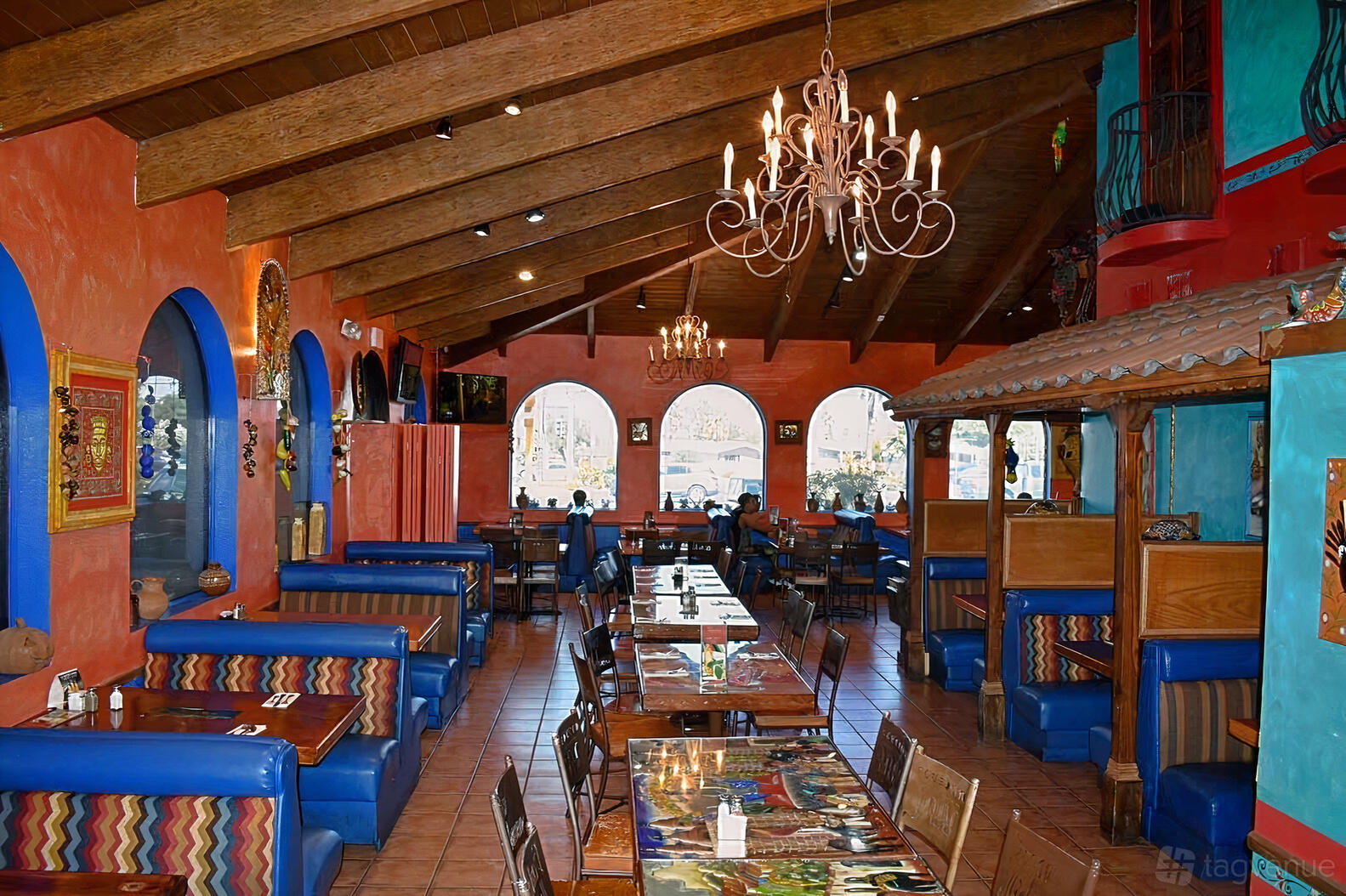 A restaurant with colorful walls, exposed wooden ceiling, chandeliers, and blue booth seating at Bonito Michoacan Mexican Restaurant.