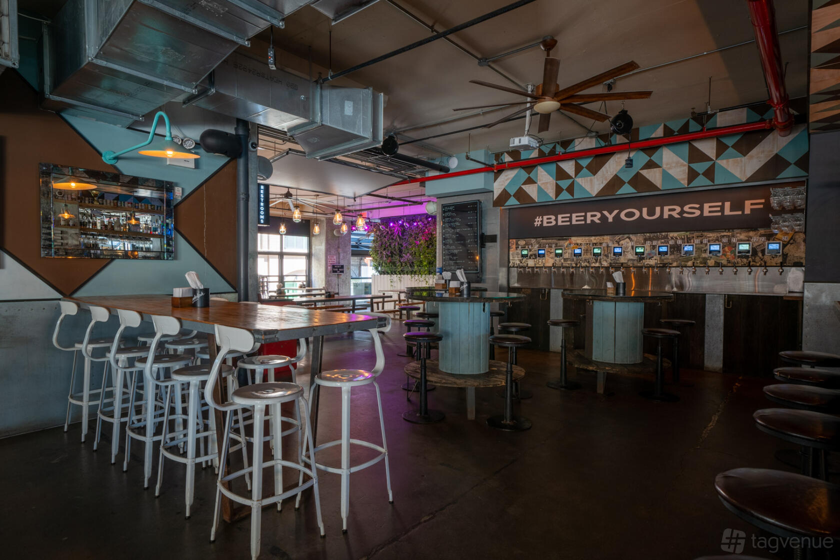 An event space in a pub with self-serve beer taps, high tables with bar stools, and industrial decor at Randolph Beer DUMBO.