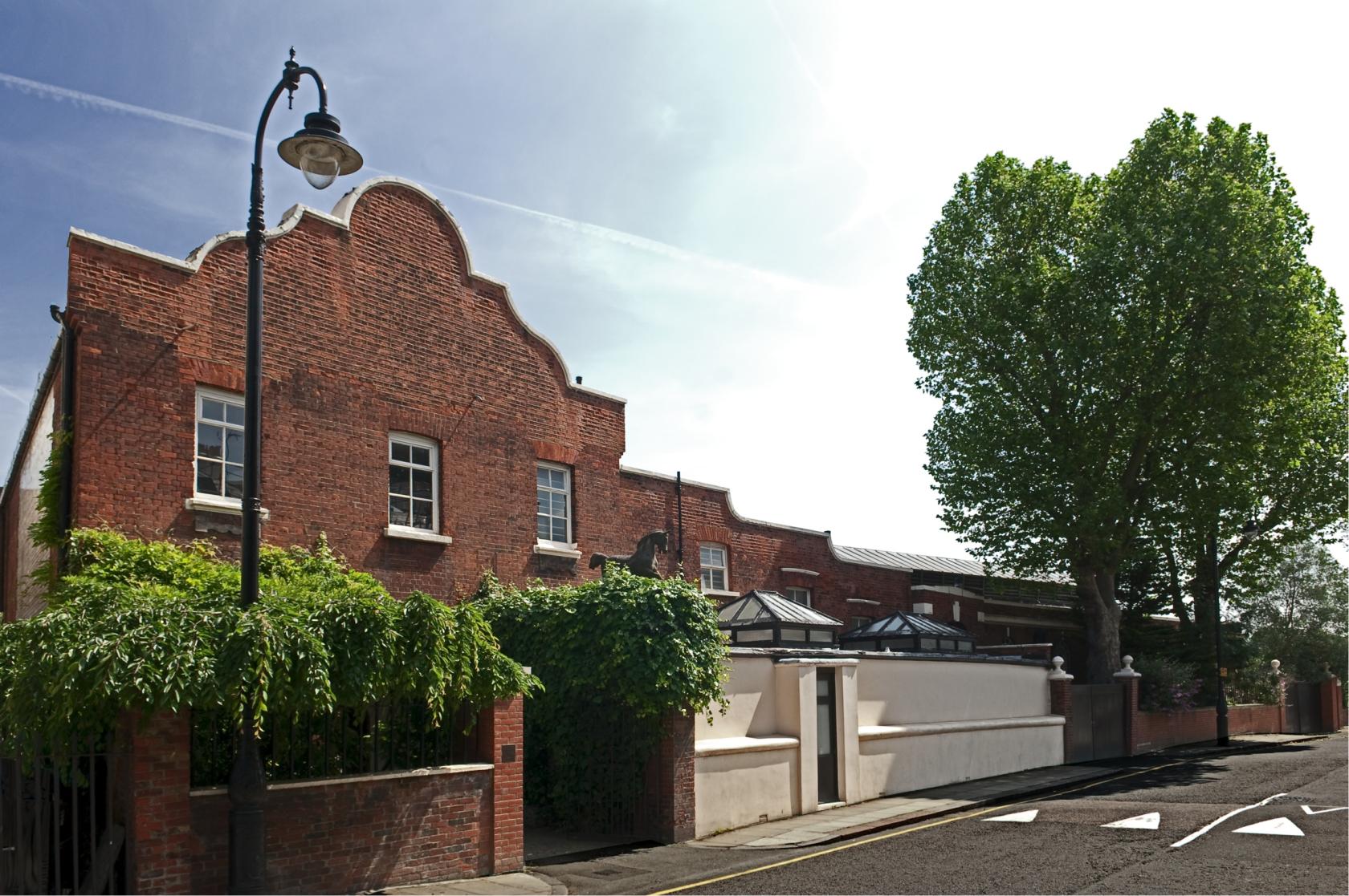 A versatile event space with a historic red brick exterior, arched gable, and leafy trees at Park Village Studios.