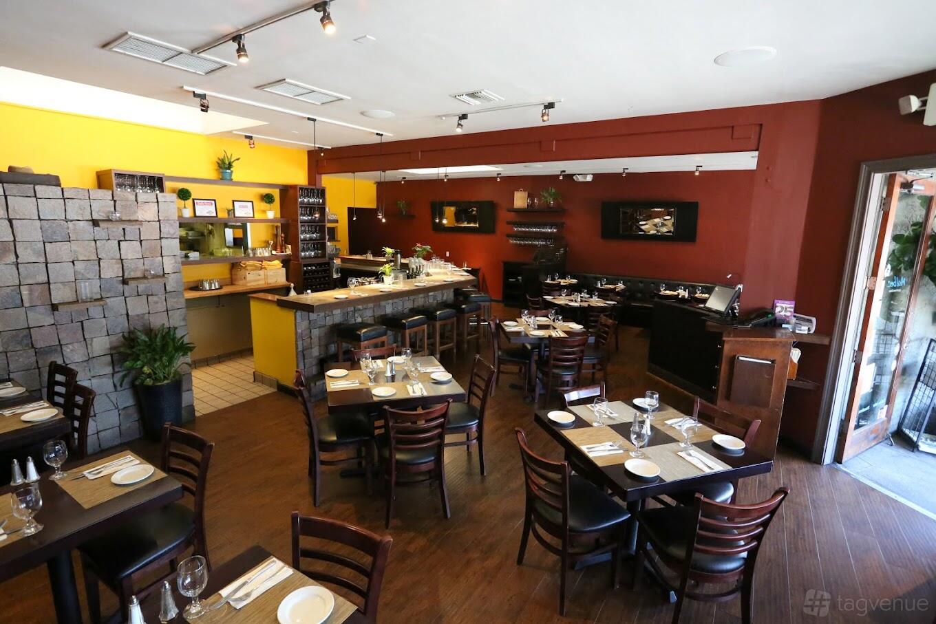 A restaurant with wooden tables, burgundy accent walls, and an open kitchen at Bodega Malbec.