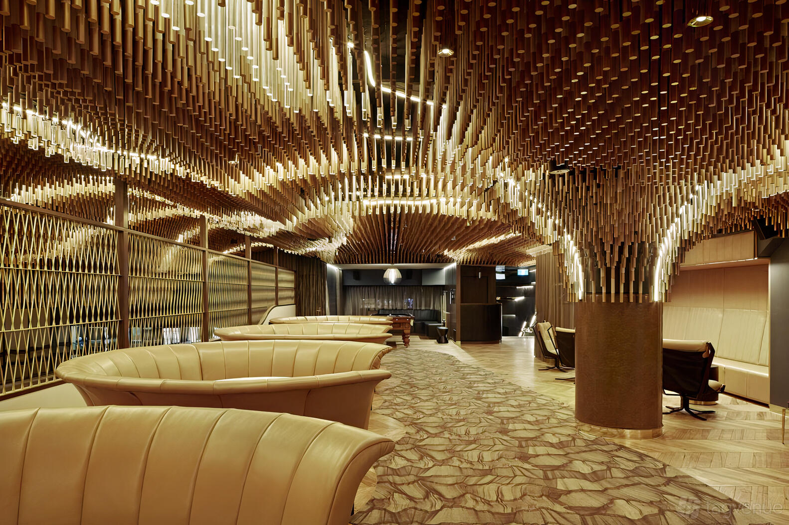 An event space with curved leather booth seating, patterned carpet, and sculptural wood ceiling details at Kingpin Crown.