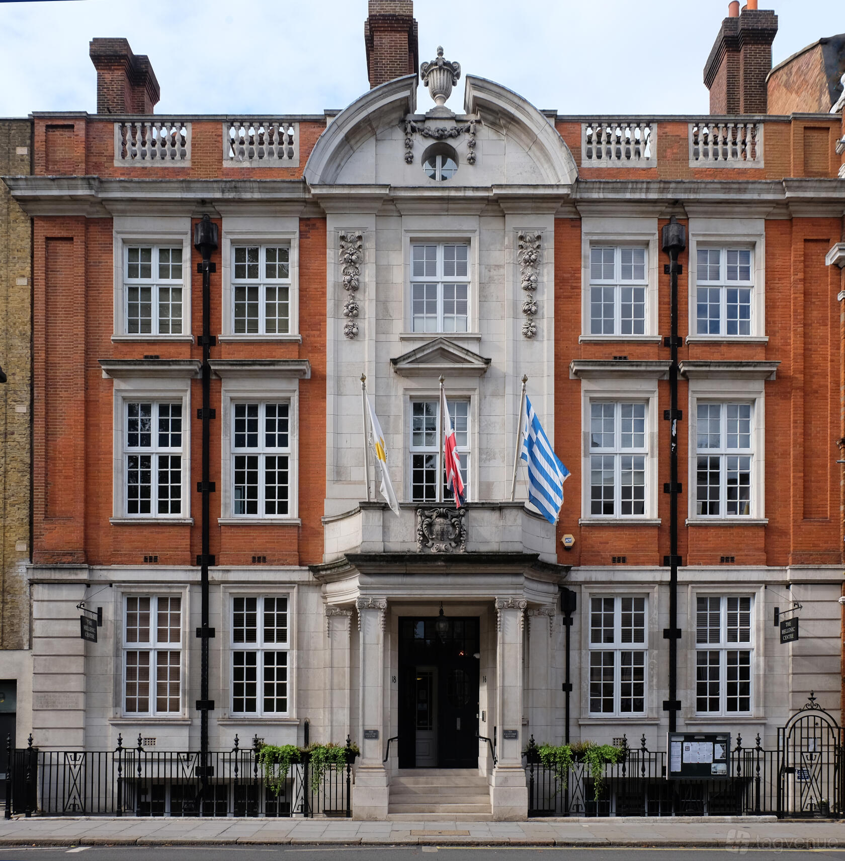 A blank canvas venue with a red brick and white stone facade, large windows, and flagpoles at Hellenic Centre.