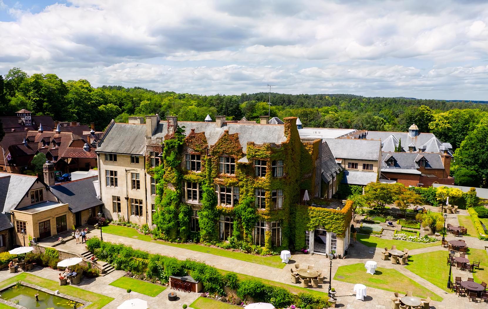 A hotel with ivy-covered stone walls, manicured lawn, and outdoor seating at Pennyhill Park.