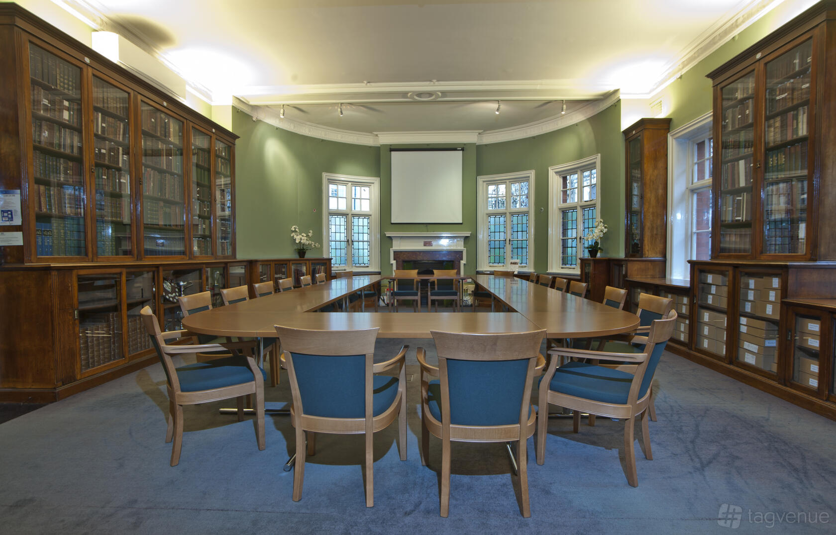 An event space in a bar with built-in bookshelves, arched windows, and a large oval meeting table at St Bride Foundation.