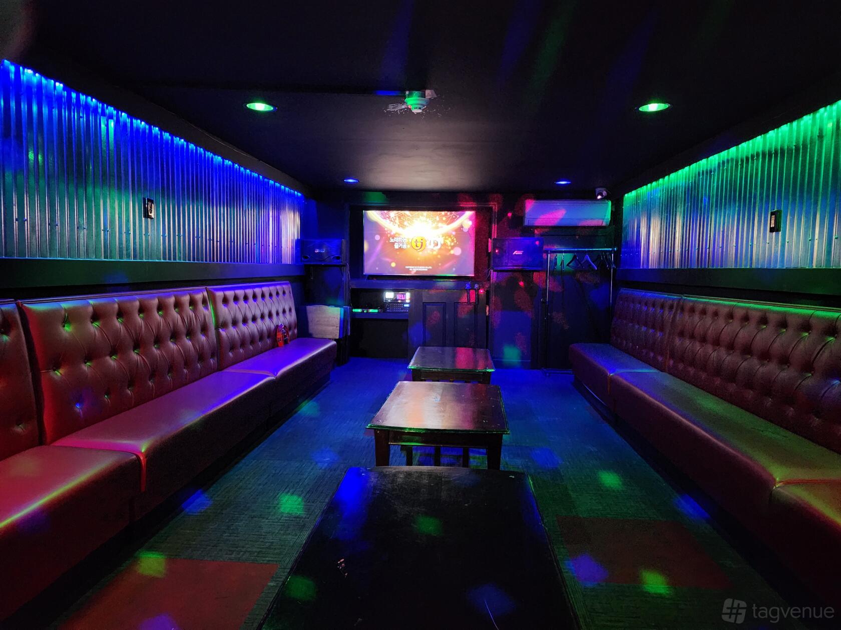 A private karaoke room with red leather banquettes, colored disco lighting, and a large projector screen at Fuji Mountain Japanese Restaurant.