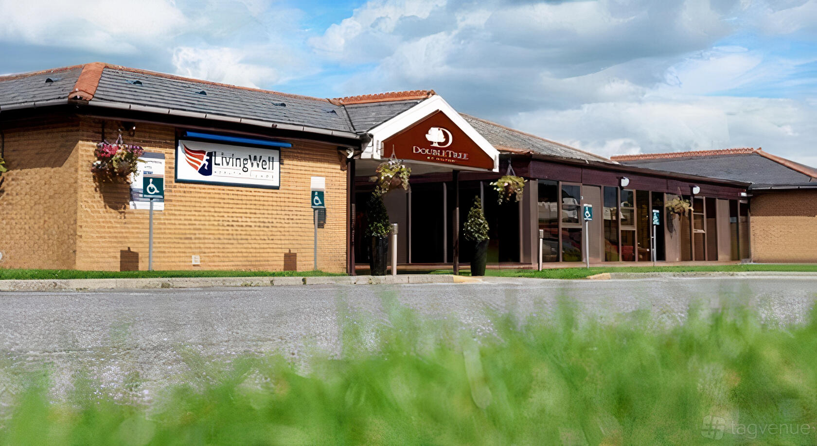 A hotel entrance with a covered walkway, hanging flower baskets, and accessible parking at DoubleTree by Hilton Bristol North.
