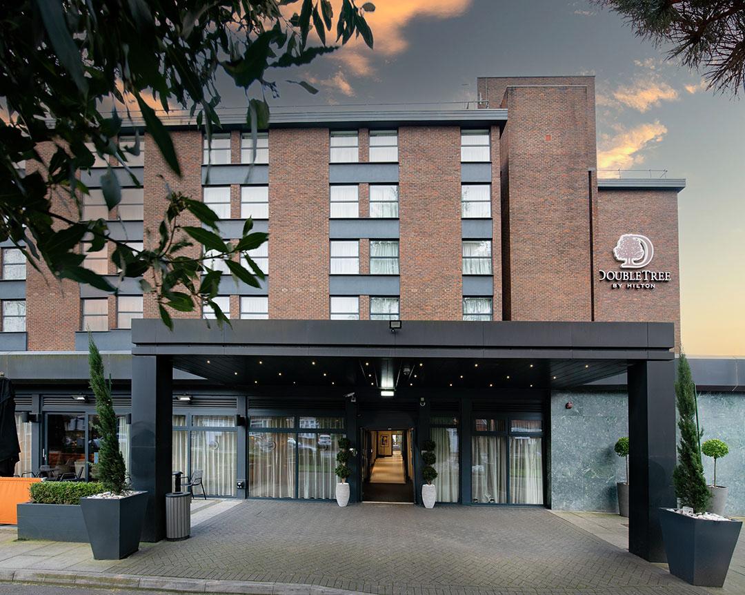 A hotel exterior with brick façade, large entryway canopy, and DoubleTree by Hilton London - Ealing signage.