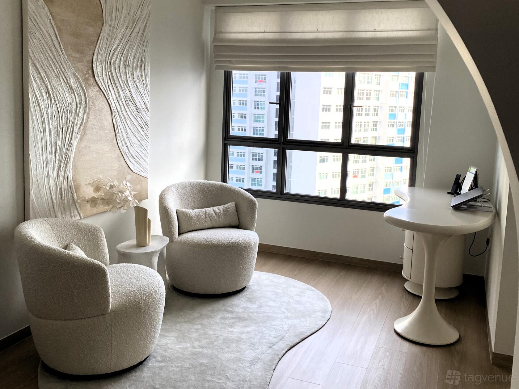 An apartment with curved white armchairs, textured wall art, a sculptural table, and large windows at Minimalist Seaview Apartment.