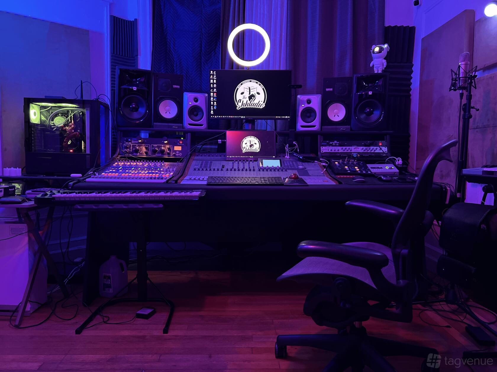A recording studio with mixing consoles, multiple studio monitors, a keyboard, and purple accent lighting at The Shhtudio.