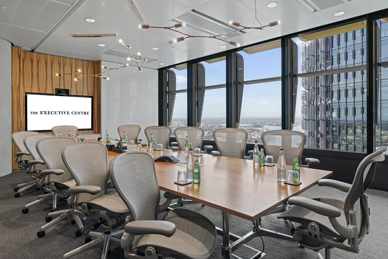 A boardroom with floor-to-ceiling windows, ergonomic chairs, and a large conference table at Three International Towers.