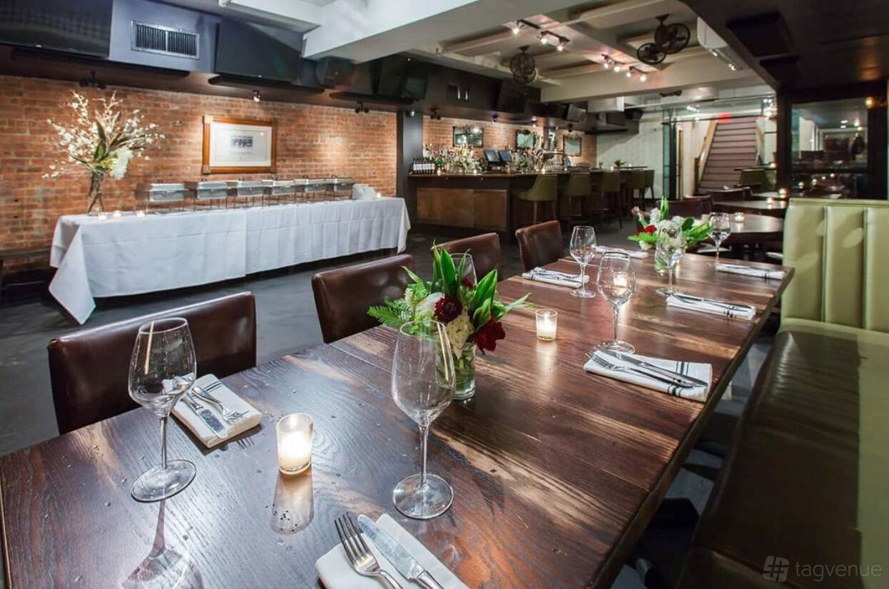 An event space with exposed brick walls, a long wooden dining table, and floral centerpieces at Croton Reservoir Tavern.