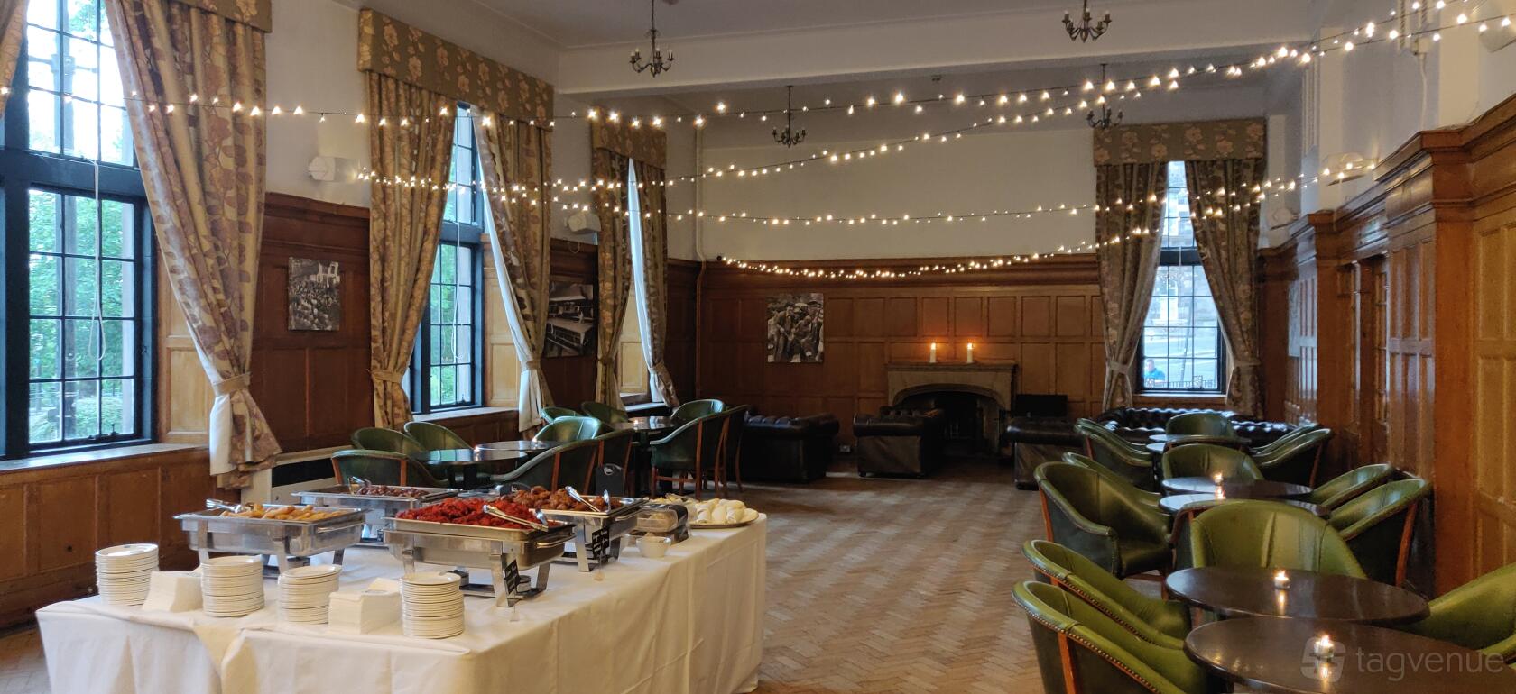 A function room with wood-paneled walls, string lights, and banquet tables at Glasgow University Union Drawing Room.