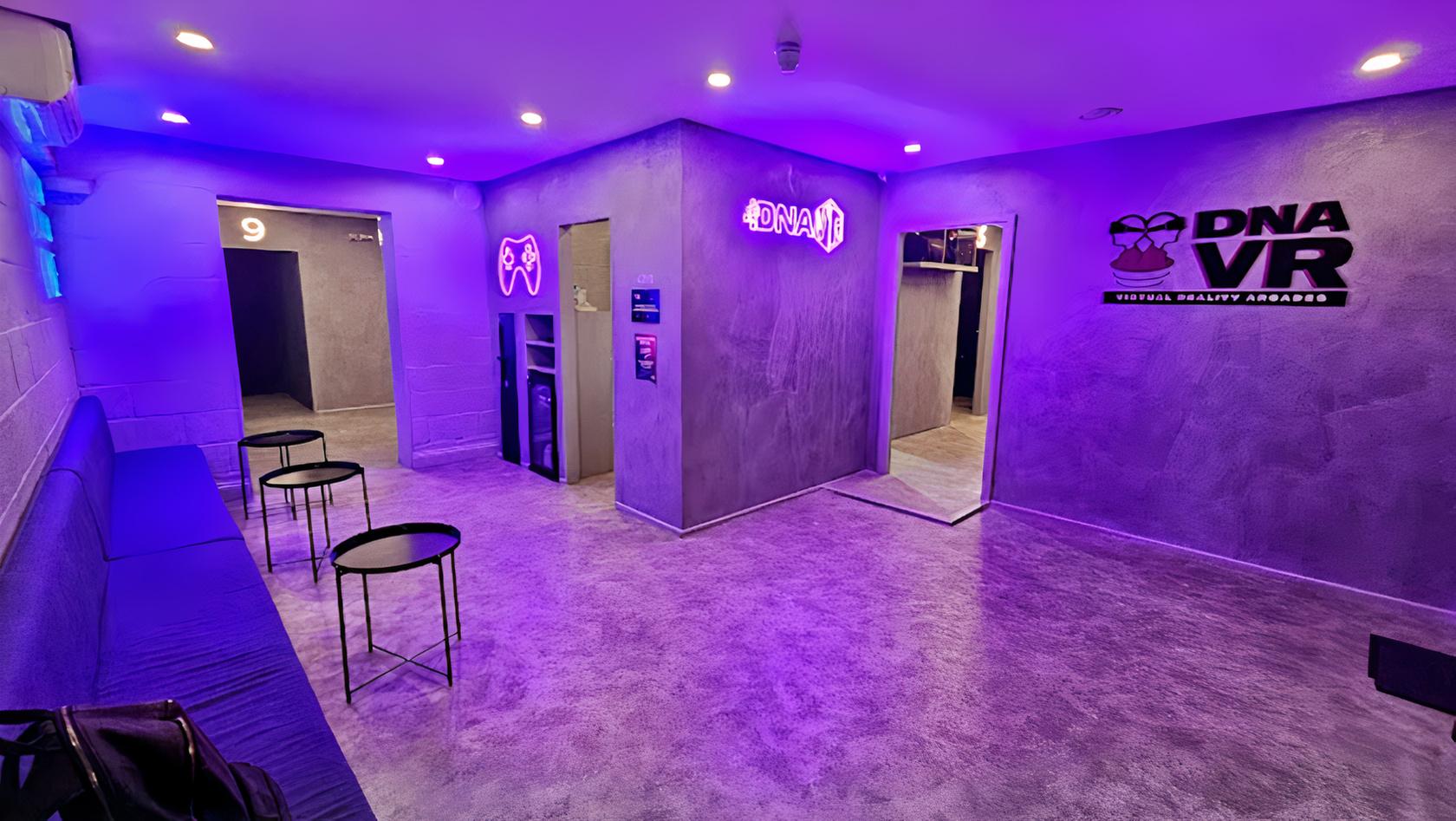 An event venue with purple LED lighting, numbered doors, and small round tables at DNA VR Camden.