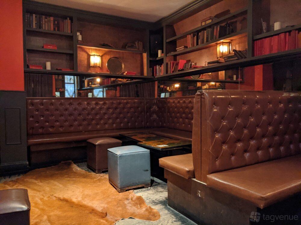 A bar with tufted leather banquettes, mirrored shelves, and warm ambient lighting at Vig Bar.