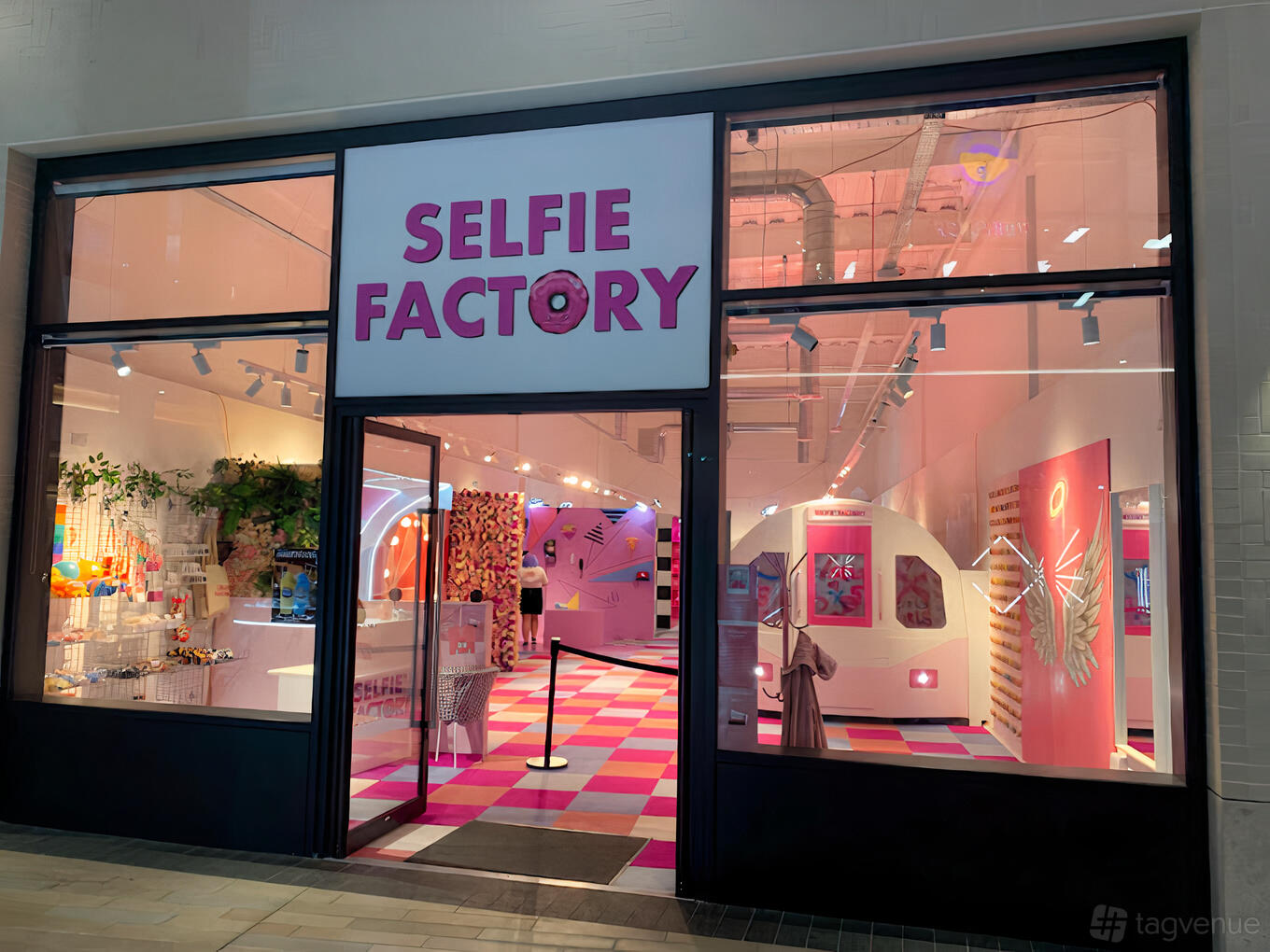 A film and photo studio with pink neon lighting, themed photo sets, and a checkered pink floor at Selfie Factory.