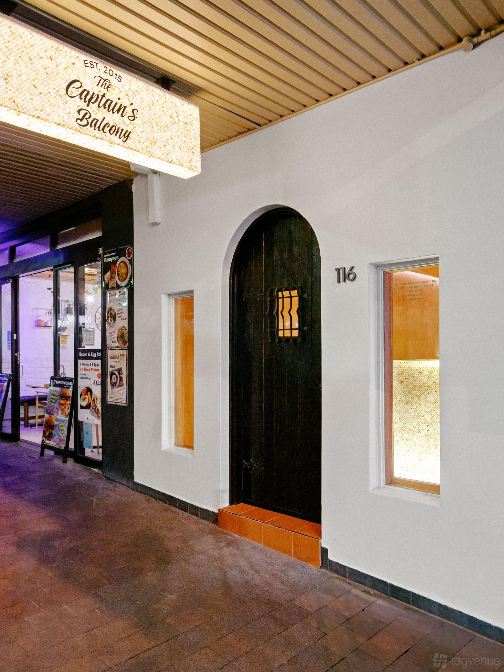 An arched black door with grid window and white facade alongside a lit window at The Captains Balcony Crows Nest.