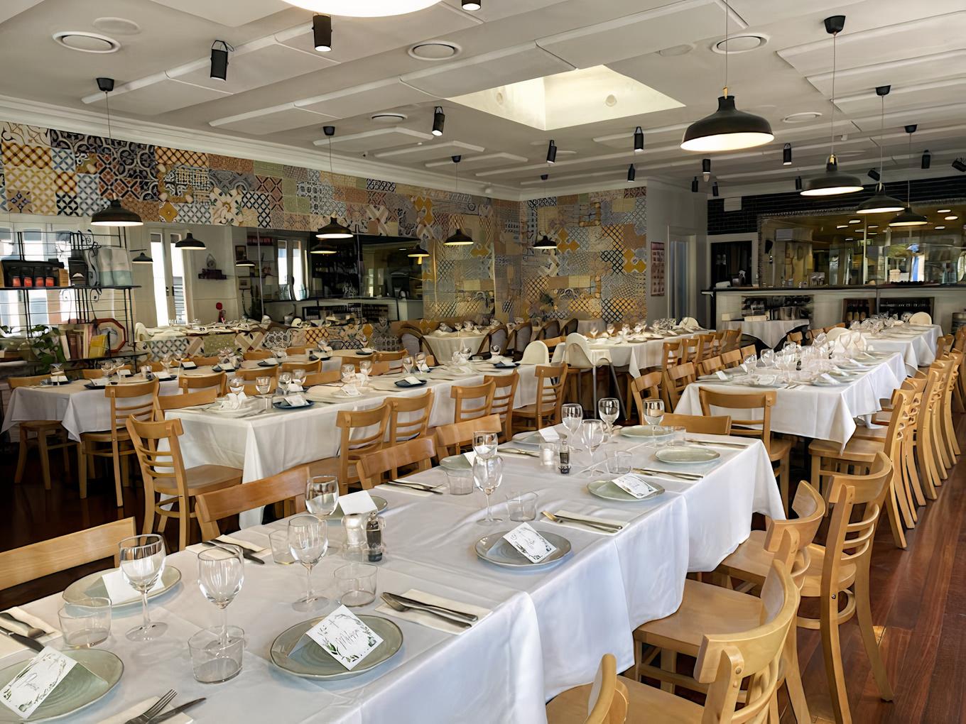 A restaurant with long banquet-style tables covered in white linens and patterned tile accent walls at Forli Ristorante.