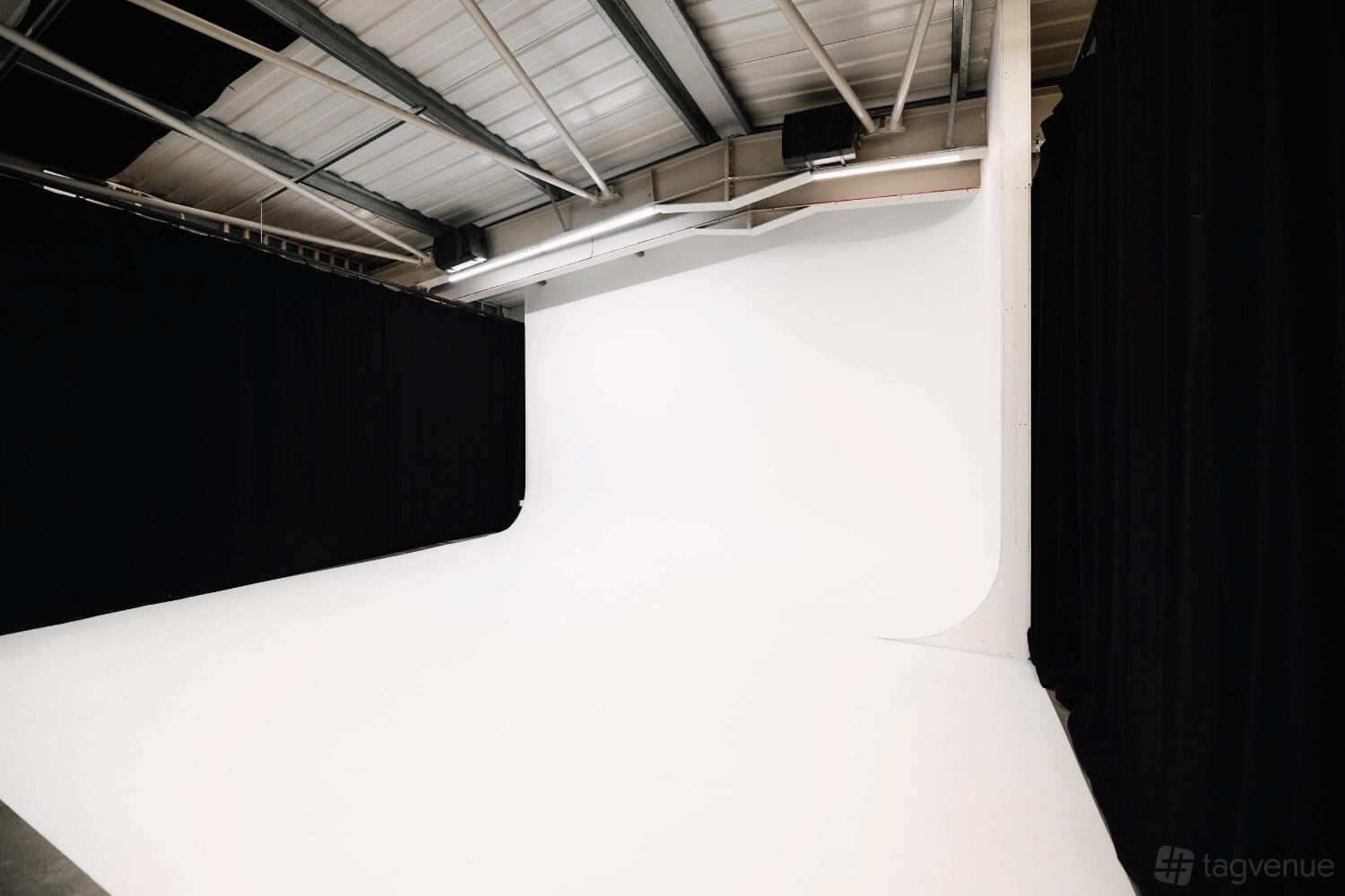 A photography studio with a white cyclorama wall, high ceiling, and black-out curtains at MAKE IT London.