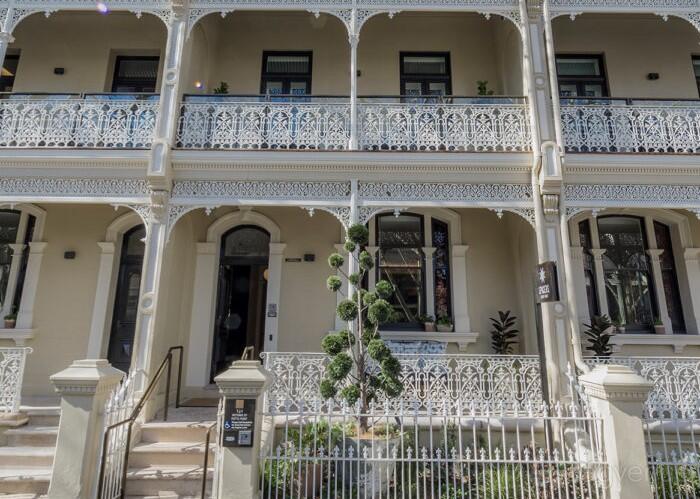 A hotel with ornate iron lace balconies, arched entryway, and manicured topiary at Spicers Potts Point.