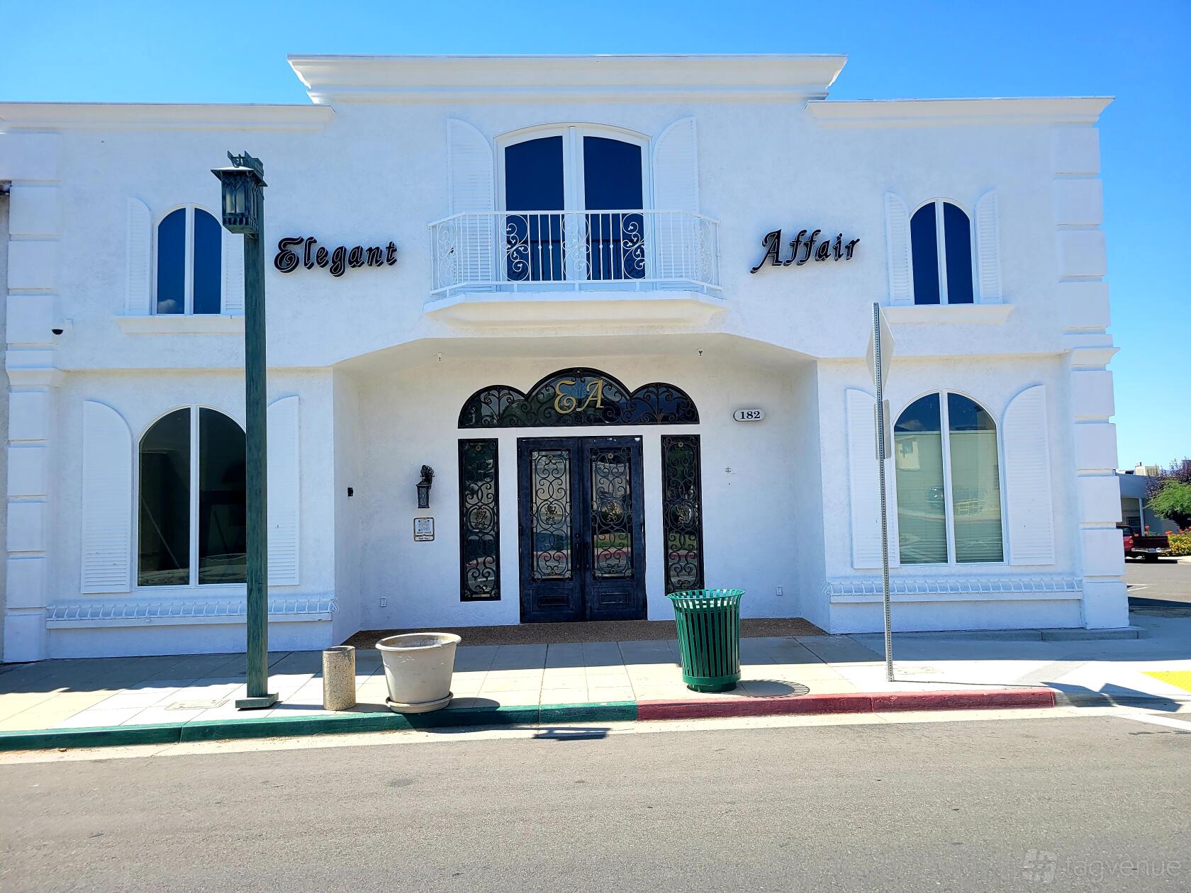 A historic building with white stucco exterior, arched windows, and ornate double doors at Elegant Affair Wedding Venue.