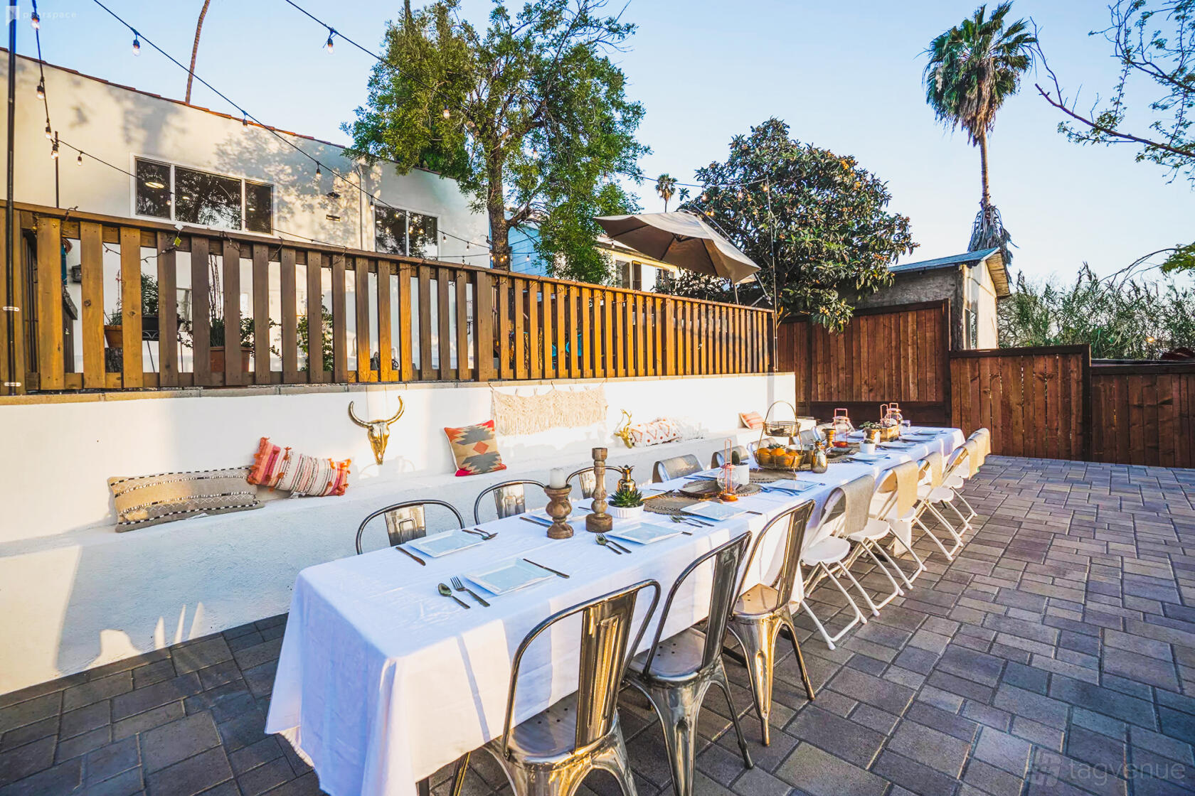 An outdoor event venue with long banquet tables, white linens, string lights, and patio seating at Hidden Gem LA.