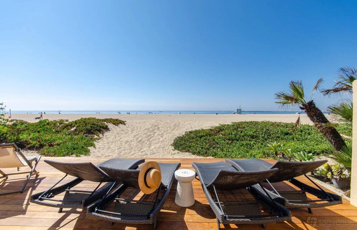 An event venue with wicker lounge chairs and beach views on a wooden deck at Modern Boho Beach House.