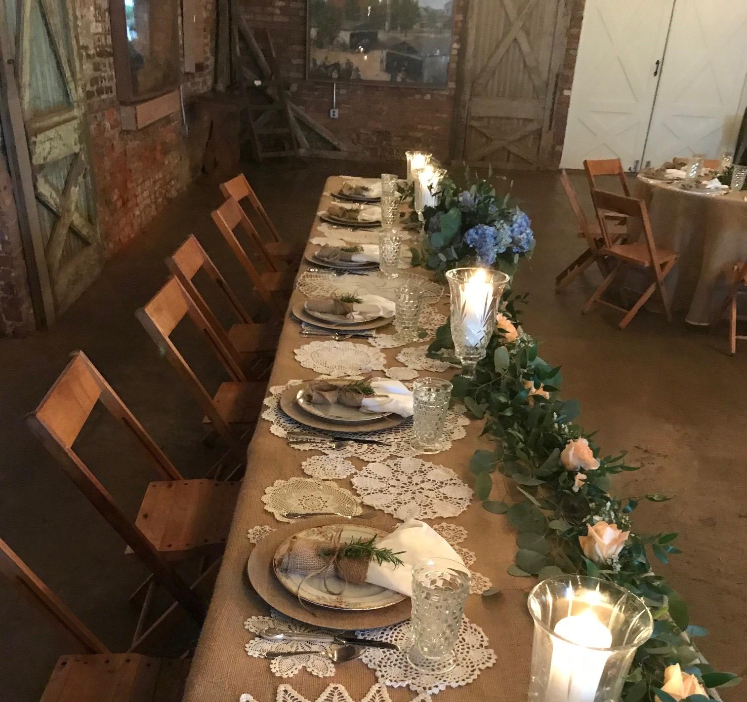 A historic building with exposed brick walls, rustic wood doors, and a long banquet table with floral centerpieces at Historic Train Depot in Newnan