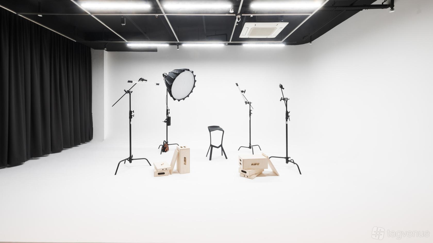 A photo studio with a white cyclorama wall, lighting equipment, and black ceiling at Siecle Studios.