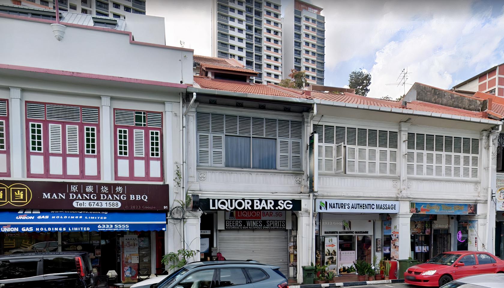 A row of shophouses with large shuttered windows and signs for various businesses at Vspace.