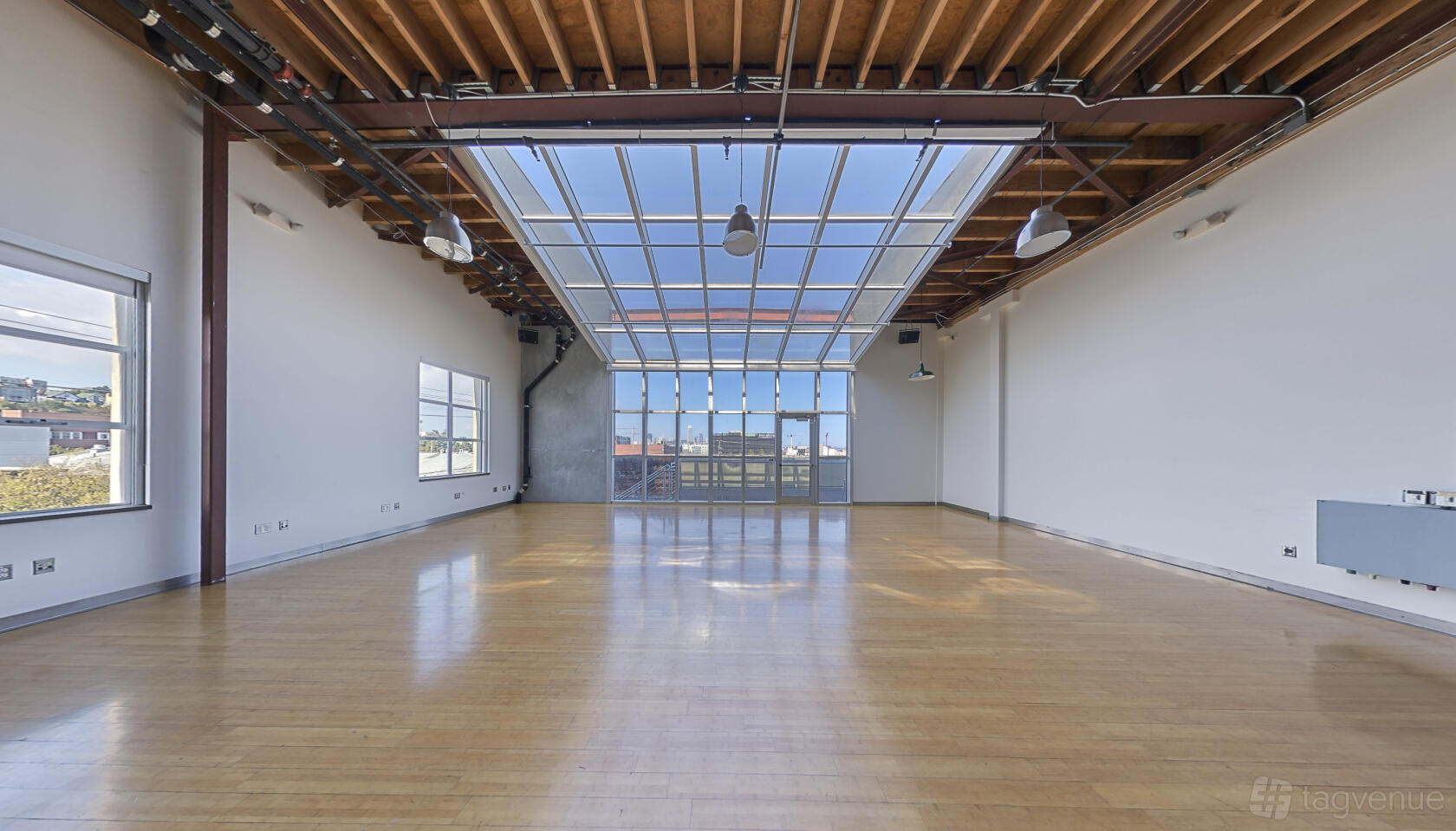 An event venue with hardwood floors, exposed beams, and a large glass ceiling on the 3rd Floor at Dogpatch Studios.