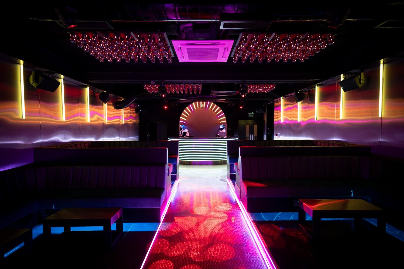 A nightclub with LED lighting, illuminated dance floor, and lounge seating facing a DJ booth at Twnty7.