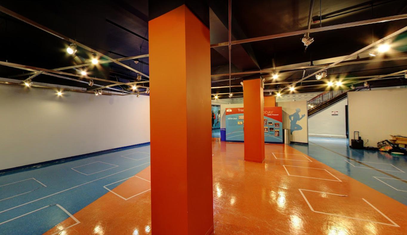 An event venue with glossy orange and blue floors, orange columns, and track-themed wall graphics at The Armory.