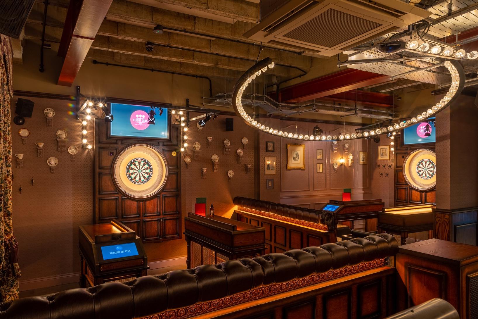 An event space in a bar with leather booths, dartboards, and decorative lighting at Flight Club Cardiff.