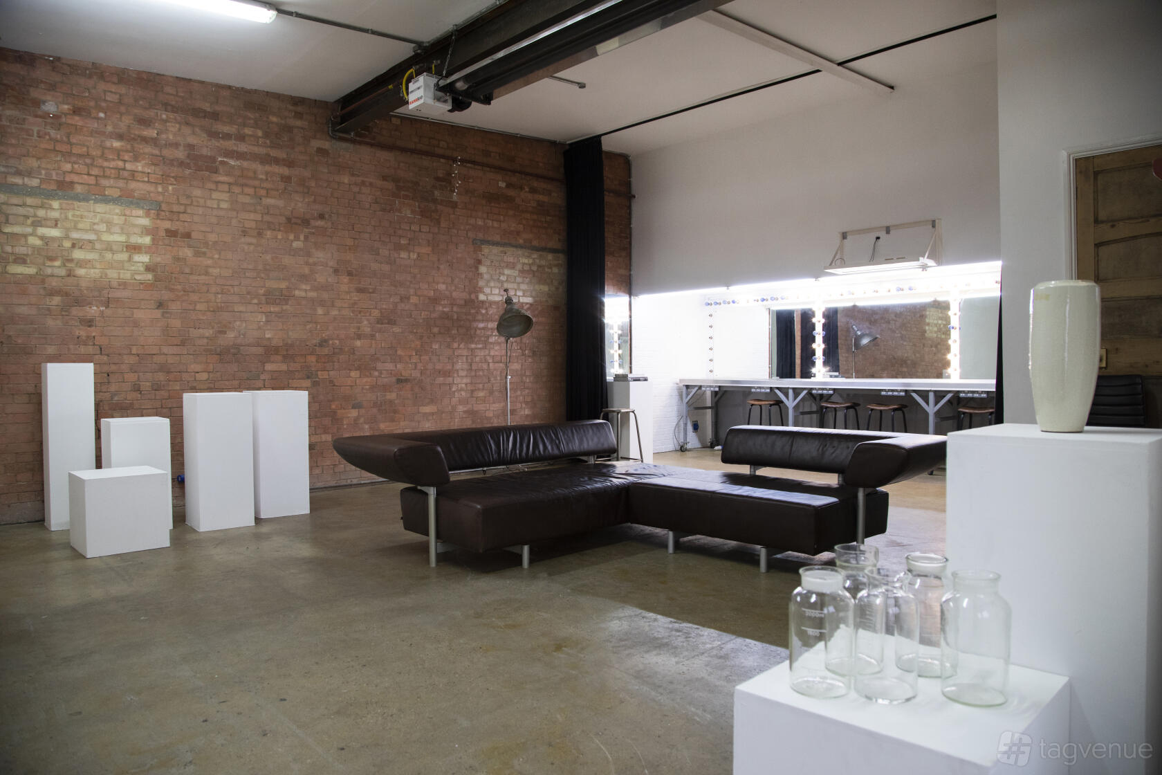 An event venue with exposed brick walls, brown leather sectional sofas, and glass display jars at Bow Bunker.