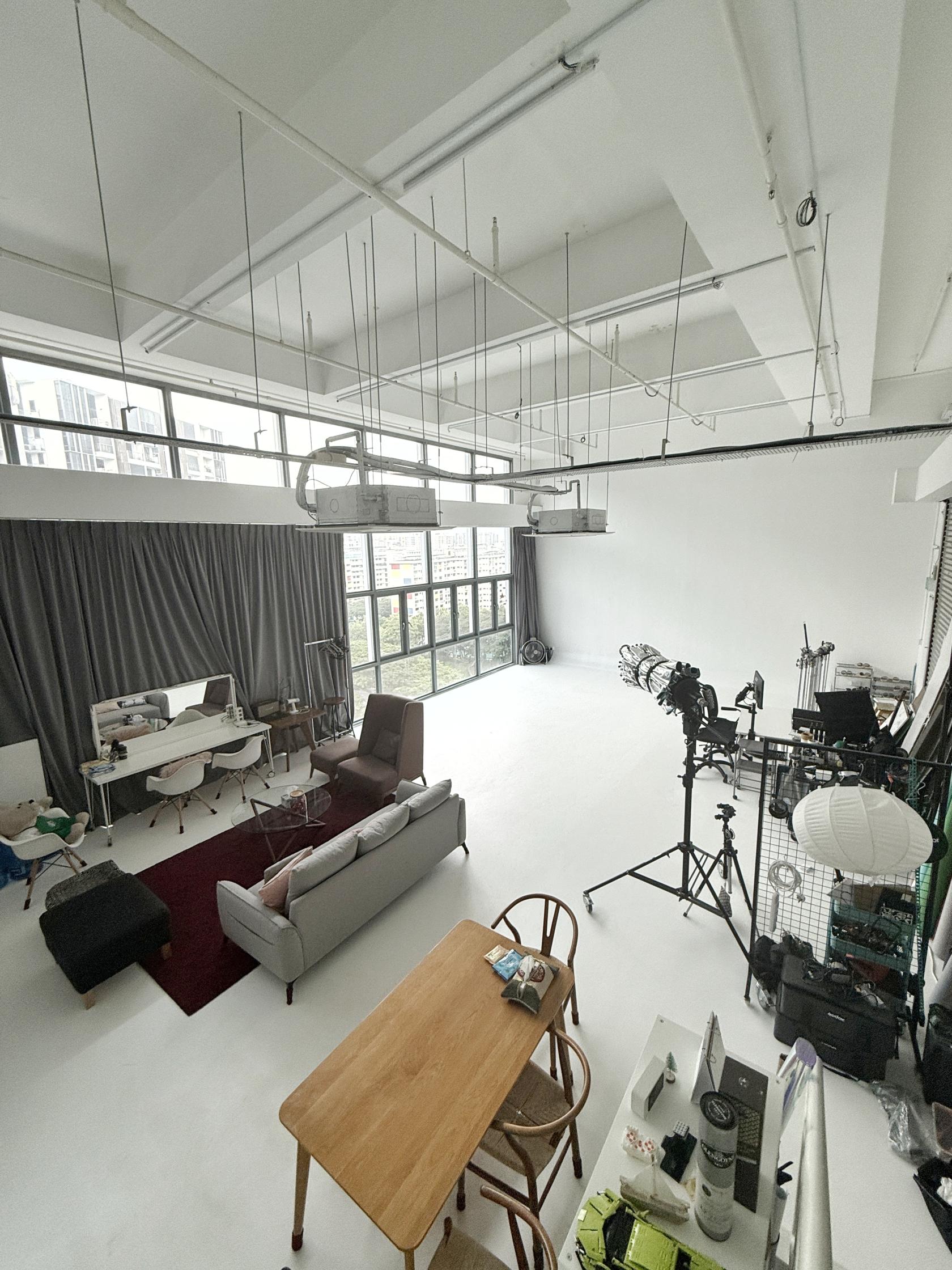 A photo studio with floor-to-ceiling windows, seamless white cyclorama, and lounge area at Studio Three Sixteen.